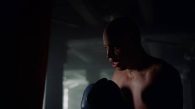 Modern spor salonunda erkek boksör tekmeleri deniyor. Kum torbasıyla dövüşen adam