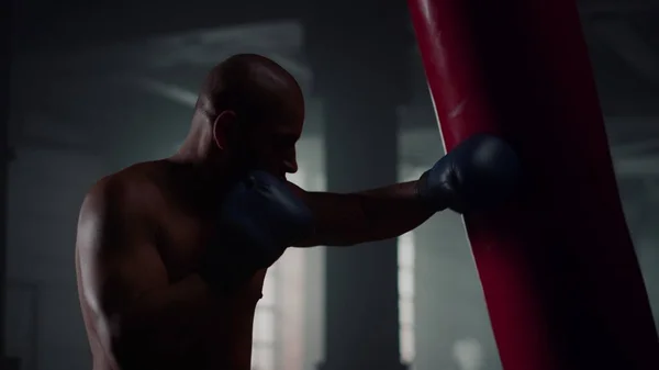 Erkek boksör boks torbası. Çıplak gövdeli bir adam spor salonunda boks antrenmanı yapıyor. — Stok fotoğraf