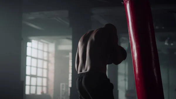 Boxer hitting punch bag during intense workout. Man practicing kickboxing in gym — Stock Photo, Image