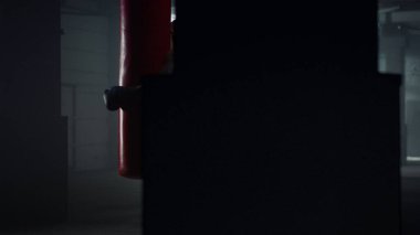 Kum torbasıyla boks antrenmanı yapan adam. Sporcu spor çantasına yumruk atıyor.