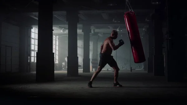 Mužský boxer mlátí sportovní tašku. Vzteklý muž pracuje na foukání na boxovací pytel — Stock fotografie