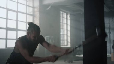 Kızgın adam çekiçle lastiğe çarpıyor. Adam fiziksel egzersiz yapıyor.