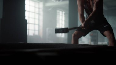Lastiğe çekiçle vuran bir adam. Atletik sporcu güç egzersizi yapıyor.
