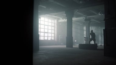 Spor adam ağır lastik lastiği kaldırıyor. Sporcu yoğun antrenman yapıyor. 