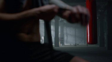 Spor salonunda boks kasetleriyle el ele tutuşan bir boksör. Kum torbası kullanan afro adam.