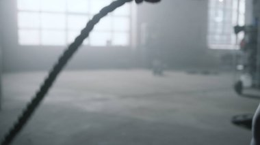 Savaş halatlarıyla çalışan bir sporcu. Crossfit egzersizi yapan kadın.