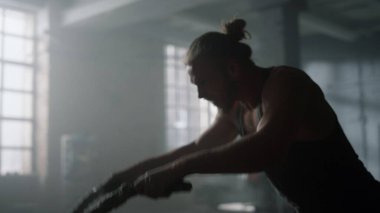 Adam savaş halatlarıyla çapraz antrenman yapıyor. Kızgın adam spor salonunda vücut çalıştırıyor.