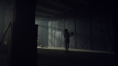 Spor salonunda topları formda yürüyen bir kadın. Sporcu kadın elinde topla duvarda duruyor.