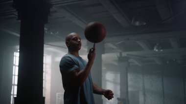 Adam parmak üzerinde basketbol topu çeviriyor. Oyuncu parmak üzerinde topu dengeliyor