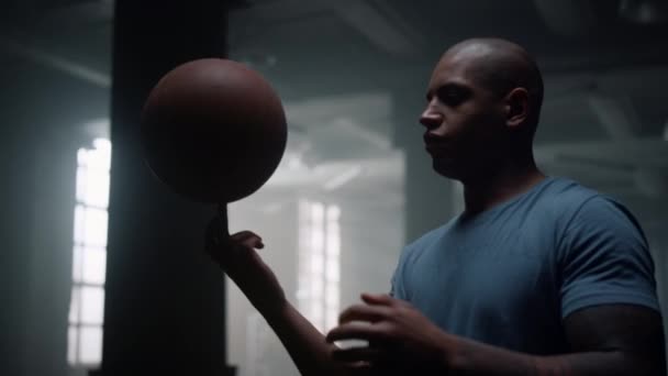 Hombre enfocado haciendo girar la bola en el dedo. Atleta haciendo truco con pelota de baloncesto — Vídeos de Stock
