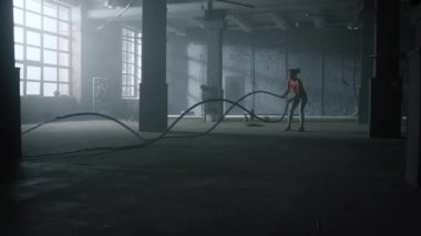Kadın savaş halatlarıyla antrenman yapıyor. Kız Crossfit egzersizi yapıyor 