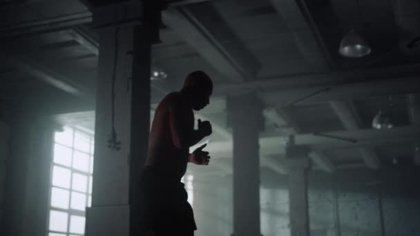 Hombre atlético entrenando boxeo en loft building. Boxeador masculino luchando con sombra — Vídeo de stock