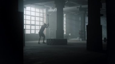 Lastik lastiği çekiçle döven bir sporcu. Balyozlu adam antrenman yapıyor.