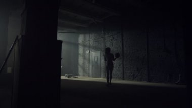 Spor salonunda topları formda yürüyen bir kadın. Sporcu kadın elinde topla duvarda duruyor.