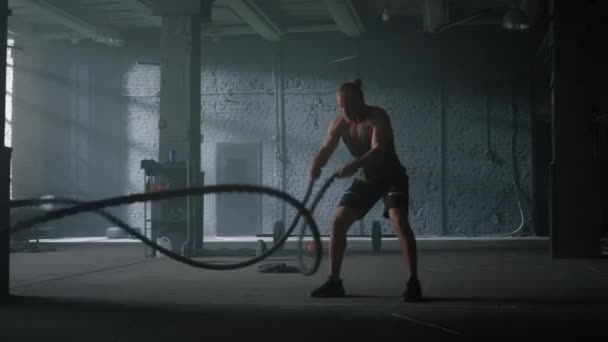 Vücut geliştirici savaş ipleriyle çalışıyor. Sporcu adam spor yapıyor. — Stok video