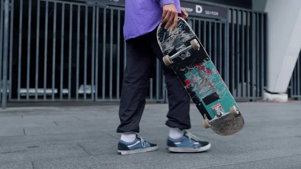 Неизвестный человек со скейтбордом на улице. Шаг скейтера с длинной доской в руке — стоковое фото