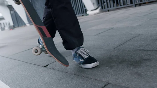 Неизвестный скейтер идет на тренировку. Мужские ноги в спортивной обуви, идущие по улице. — стоковое фото