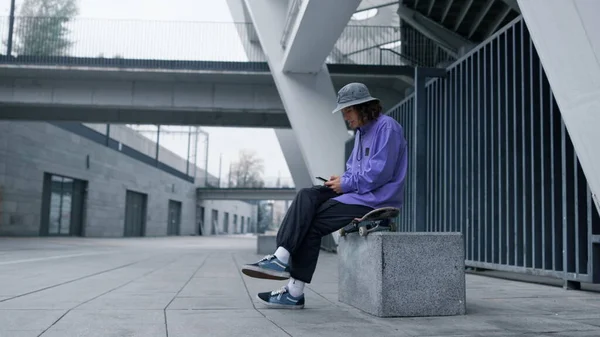 Hombre enfocado mirando la calle de la ciudad. hipster con estilo utilizando el teléfono celular al aire libre. — Foto de Stock