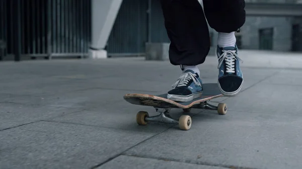 Unknown skater riding on board outdoor. Unrecognizable man feet skating outside.