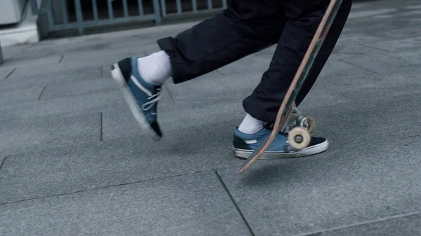 Skater irreconhecível balanceamento a bordo ao ar livre. Homem pés correndo fora. — Fotografia de Stock