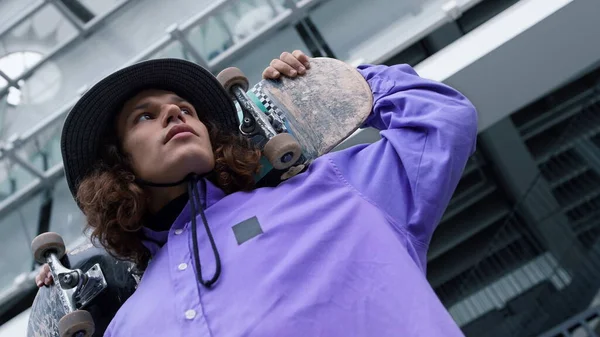 Homem skater jovem olhando câmera ao ar livre. Tipo a pensar no novo truque lá fora. — Fotografia de Stock