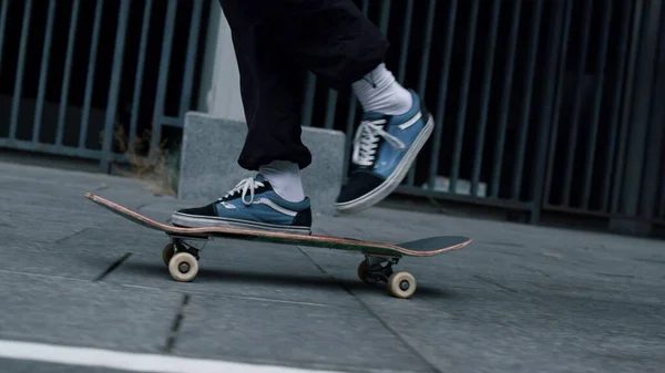 Patinador irreconhecível pulando em longboard. Homem ativo fazendo kickflip fora. — Fotografia de Stock