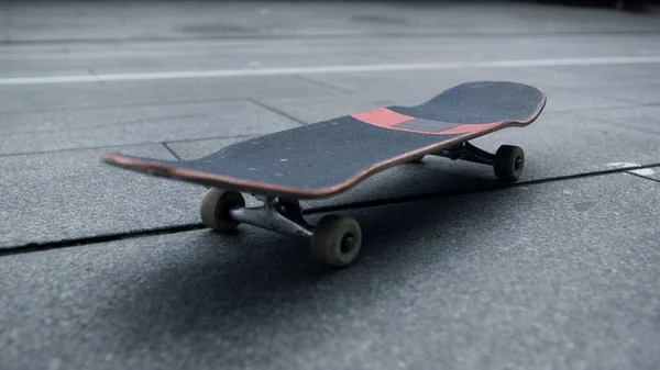 Tablero negro con ruedas blancas alojadas en la calle de la ciudad. Skateboard para trucos. — Foto de Stock