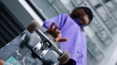 Bilinmeyen hipster dışarıda sörf tahtası çeviriyor. Adam dışarıda paten kayıyor..