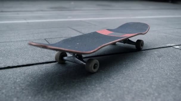 Placa preta com rodas brancas ficando na rua da cidade. Skate para truques. — Vídeo de Stock