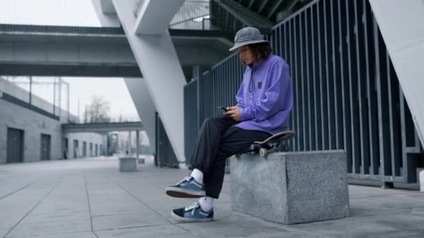 Стильный мужчина смотрит на экран телефона на открытом воздухе. Сообщение от скейтера на смартфоне. — стоковое видео