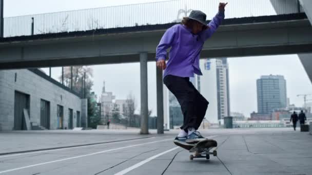 Sportovní bruslař dělat trik na palubě venkovní. Skateboard na asfaltu. — Stock video