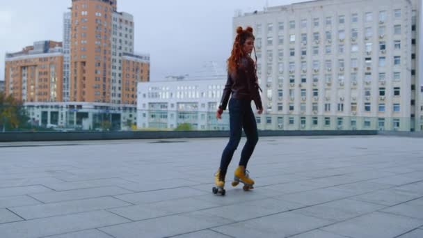 Patenlerle dans eden aktif kızıl kadın. Patenci kız şehirde daireler çiziyor. — Stok video