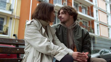 Bankta öpüşen sevimli bir çift. Romantik çift şehirde göz göze gelir..