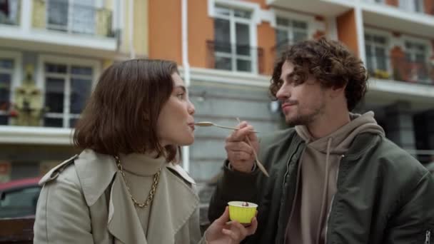 Fröhliches Paar beim Eis essen im Freien. Fröhliches Paar küsst sich auf Stadtstraße. — Stockvideo