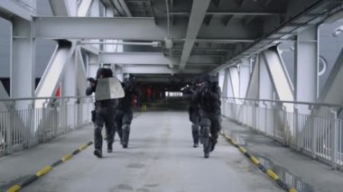 SWAT ekibi köprüde yürüyor. Tüfek kullanan maskeli askerler 
