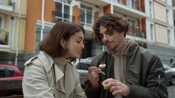 Прекрасная пара проводит время на улице. Мужчина кормит женщину на фоне города. — стоковое видео