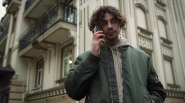 Şehir caddesinde telefonla konuşan ciddi bir adam. Açık havada akıllı telefon kullanan odaklanmış bir adam..