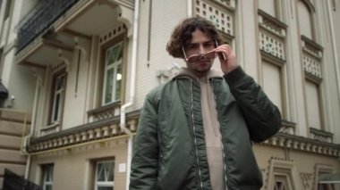 Dışarıdaki kameraya bakan ciddi bir adam. Şık hippi güneş gözlüğü takıyor..