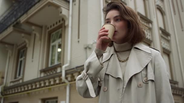 Νεαρή γυναίκα πίνει καφέ για να βγει στο δρόμο. Κορίτσι απολαμβάνοντας ζεστό latte εξωτερική. — Αρχείο Βίντεο