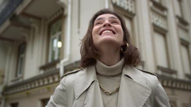 Dışarıdaki kameraya bakan mutlu kadın. Şaşkın kız bahar gününde şehrin tadını çıkarıyor..