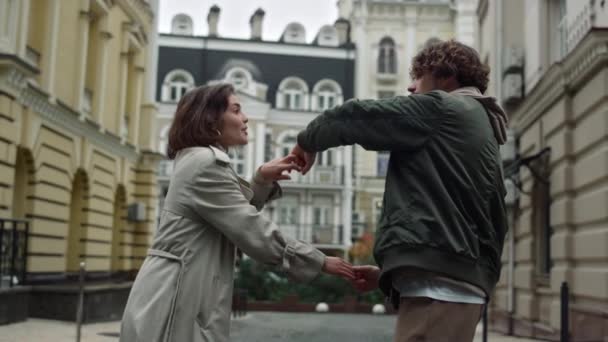 Hermosa pareja bailando en el fondo de la ciudad. Hombre y mujer tomados de la mano al aire libre. — Vídeos de Stock