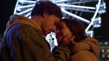 Şehir caddesinde göz göze gülümseyen bir çift. Erkek kadına dokunuyor..