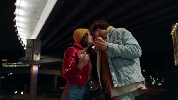 Pareja alegre besándose en la calle urbana. Hombre y mujer disfrutando de bocadillos. — Vídeos de Stock