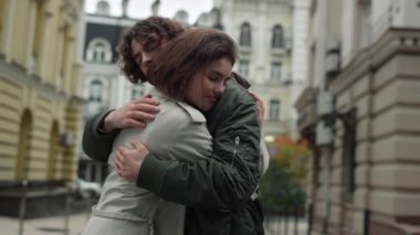 Sokakta kucaklaşan sevgi dolu bir çift. Şehrin arka planında kadını çevreleyen adam.