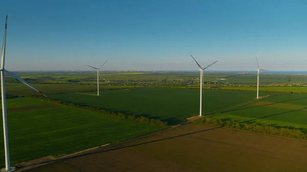 Spinning wind towers generating energy in fields. Drone view of wind turbines.