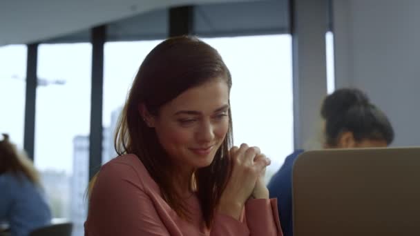 Bizneswoman siedzi w miejscu pracy. Uśmiechnięty pracownik patrzący na ekran laptopa — Wideo stockowe