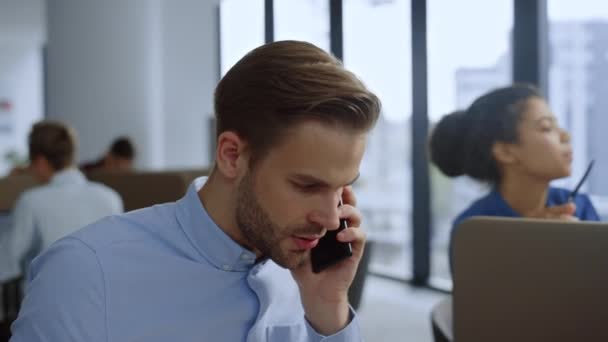 Affärsman som pratar i mobiltelefon på arbetsplatsen. Team som arbetar i det öppna rummet — Stockvideo