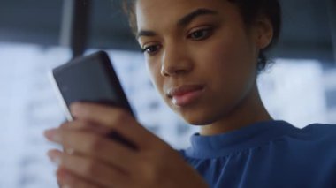 Ofisteki akıllı telefondan internete göz atan düşünceli bir iş kadını.