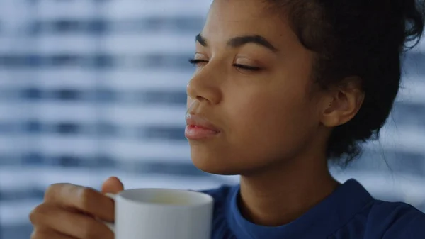 Афроамериканська бізнес-леді тримає чашку кави. Жінка працівник кусає губи — стокове фото
