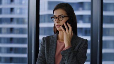 Ofisteki iş ortağıyla cep telefonunda konuşan hoşnutsuz bir iş kadını.